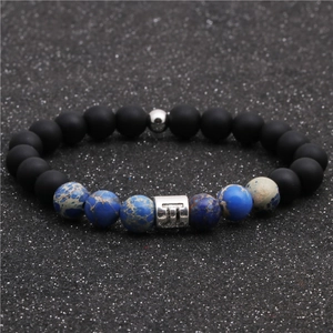 Macro detail of Gemini zodiac bead on matte black and blue imperial stone beaded bracelet