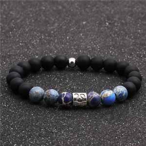 Macro shot of matte black beads and blue imperial stone bracelet with Leo zodiac sign