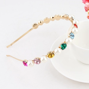 Macro view of gold metal headband with colorful rhinestones and faux pearls detail