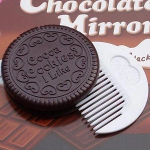 Close-up of chocolate cookie shaped folding mirror and white comb set for travel