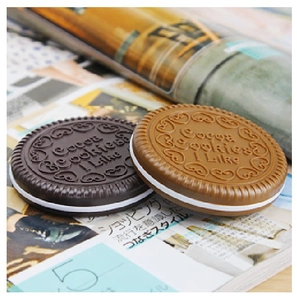 Detail of cocoa cookies shaped mini folding mirror and comb set on magazine