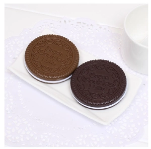 Detailed close-up of chocolate cookie shaped compact mirror and hair comb on white plate