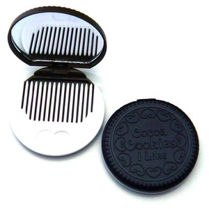 Macro detail of cookie-shaped portable makeup mirror with a white comb and glass mirror