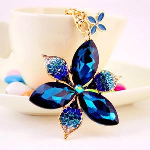 Blue crystal flower keychain with sparkling rhinestones and gold plating on white surface