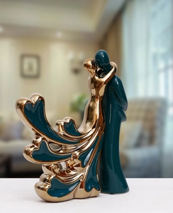 Detailed view of the electroplated gold heart pattern on a dark green ceramic couple figurine