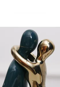 Close-up of modern ceramic couple sculpture featuring matte teal and golden electroplated finish