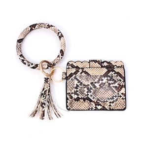 Detailed macro view of snakeskin pattern card holder with gold ring and leather tassel