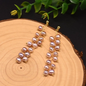 Detail of long drop earrings featuring natural purple baroque pearls and 18k gold plating