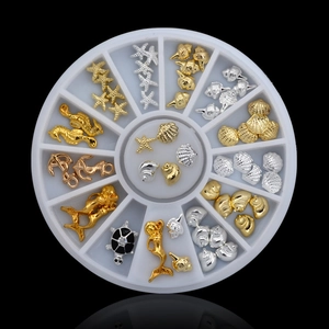 Detailed view of ocean-themed gold and silver metal nail art studs in a 12-slot wheel box