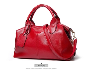 Macro shot of red lychee textured Boston bag with round handles and gold hardware