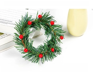 Macro detail of artificial pine needles and red berries on a small Christmas candle ring