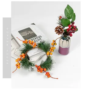 Artificial Christmas wreath and pine needle bouquet with berries in a ceramic vase