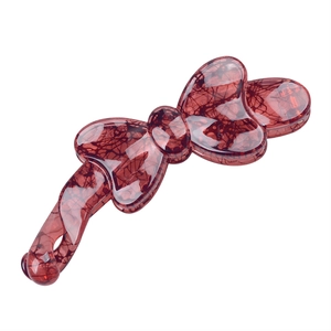 Detailed view of a red-brown resin bow banana clip with elegant marble texture