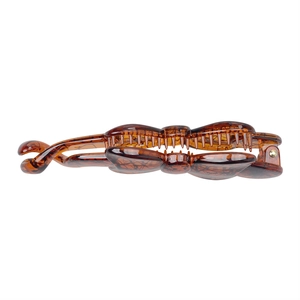 Detail view of brown amber resin banana hair clip with bow design and metal spring