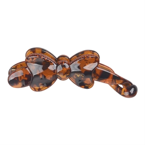 Macro detail of tortoiseshell resin banana hair clip with a bow design and glossy finish