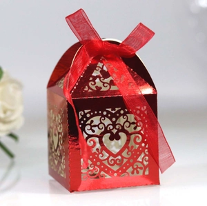 Detail of red laser-cut wedding candy box featuring a heart pattern and silk bow