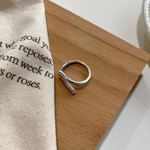 Artistic 925 sterling silver geometric crisscross ring on warm wooden surface