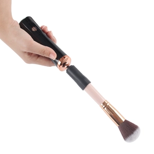 Detail van een elektrische make-up kwastreiniger met zwart handvat en roségouden ring