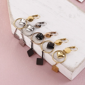 Minimalist geometric heart earrings in silver, gold, and black finishes on wood