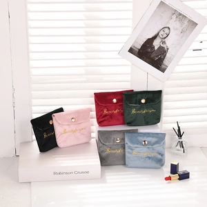 Detail view of colorful velvet cosmetic pouches with gold embroidery and snap buttons