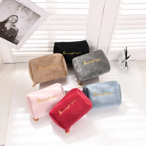 Detail view of plush velvet makeup bags in various colors with golden embroidery