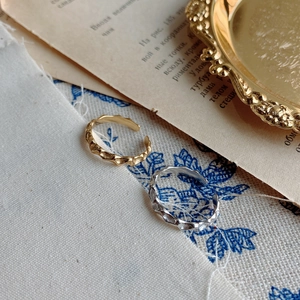 Detail of irregular hammer textured gold and silver open rings with wavy edges