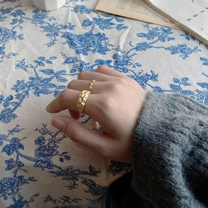 Irregular textured gold hammer ring for women worn on the finger in a cozy setting