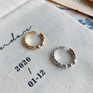 Close-up of gold and silver irregular hammered open rings on a minimalist fabric background