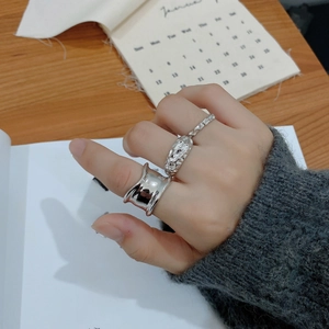 Macro shot of silver irregular rings styled on hands with a vintage magazine backdrop