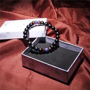 Detail of beaded yoga bracelet featuring black matte beads on a white marble gift box