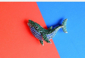 Detail of whale brooch featuring blue and green rhinestones on vintage silver metal