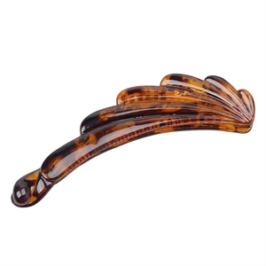 Detail of amber banana hair clip featuring resin shell texture and wavy silhouette