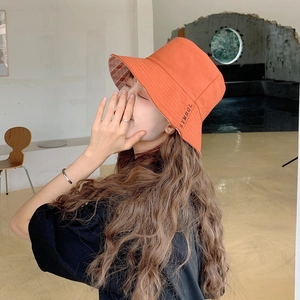 Dettaglio cappello da sole arancione con ricamo SYMBOL e fodera a quadretti bianchi e rossi