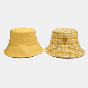 Dettaglio dei cappelli a secchiello reversibili gialli e a quadretti con patch