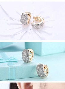 Macro detail of gold pave zircon earrings showing exquisite stones and luxury blue gift box