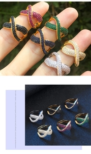 Dettaglio anello a forma di X con zirconi multicolore su fascia placcata in oro