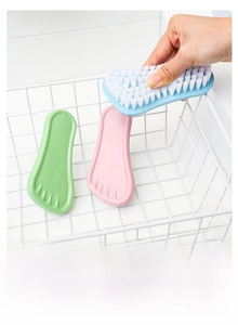 Close-up of foot-shaped cleaning brush with stiff white bristles for versatile household use