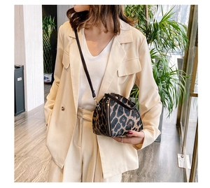 Detailed close-up of leopard print triangular crossbody bag with metallic zipper and slim strap