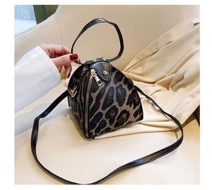 Detail of a mini leopard print triangle handbag with black straps and zipper closure