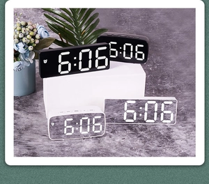 Detailed view of LED mirror alarm clocks in black and white styles on a grey surface