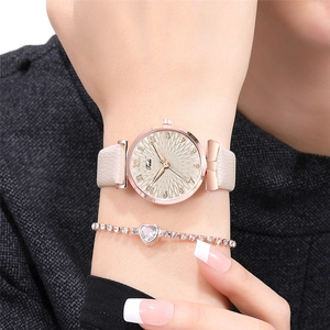 Close-up of rose gold watch with bow detail, pink leather strap, and heart bracelet