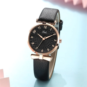 Close-up of black dial watch with rose gold case and golden bow on black leather strap