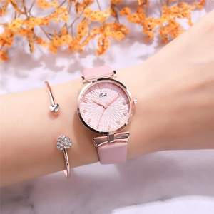 Close-up of stylish pink leather watch with rose gold bow detail and heart bracelet