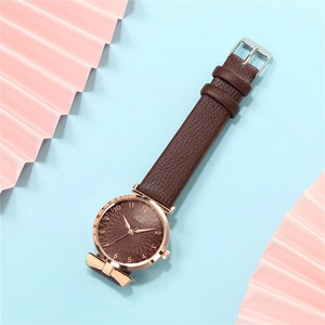 Macro shot of rose gold ladies watch with brown leather strap on blue background