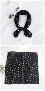 Detail of square black silk scarf with white heart pattern in folded and flat view