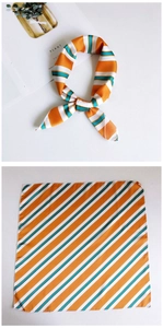 Close-up of a striped silk scarf with orange and cyan diagonal patterns and smooth texture