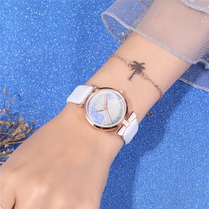 Detail of rose gold watch with tropical leaf pattern and matching palm tree bracelet