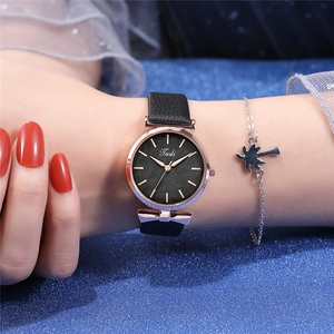 Close-up of Tadi leather watch with leaf pattern dial and palm tree charm bracelet