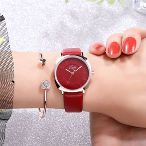 Detail of red leather watch and rose gold heart bracelet set on sparkling background