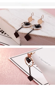 Detail of rose gold geometric heart drop earrings with black finish and long pendant